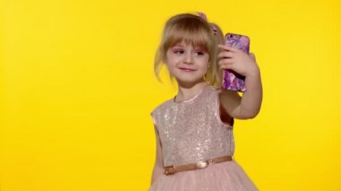 Akıllı telefon kullanan bir kız çocuğu. Sarışın çocuğun portresi cep telefonunda özçekim yapıyor.