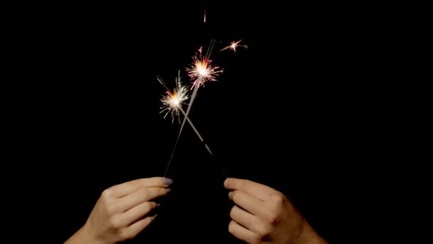 Hands holding and waving Bengal fires. New year sparkler candle burning on a black background — Stock Video