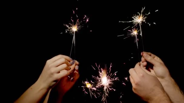 Close-up van handen houden en zwaaien bengaalse vuur branden sterretjes in de voorkant van zwarte achtergrond — Stockvideo