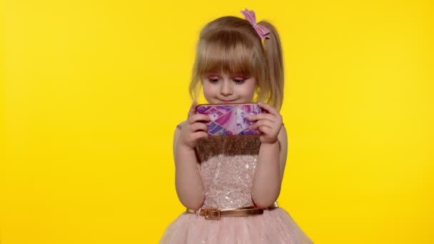 Jenta bruker smarttelefon. Barnemelding på smarttelefon. Barn som spiller spill på mobiltelefon i studio – stockvideo