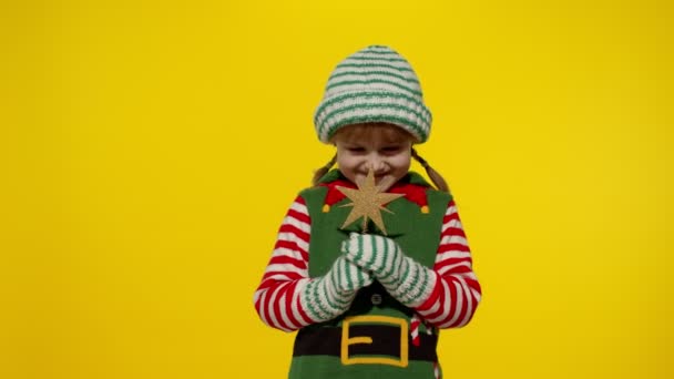 Kid girl in Christmas elf Santa helper costume holding star toy and making a wish. New Year holiday — Stock Video