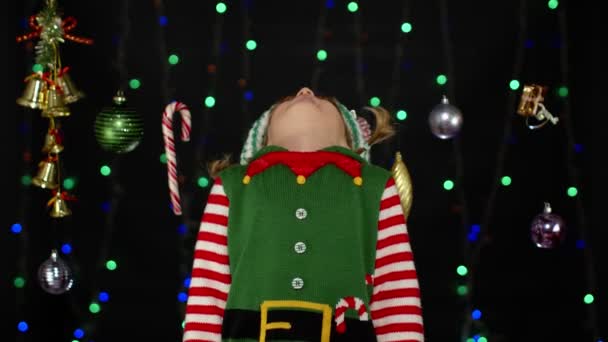 Παιδί κορίτσι σε Χριστουγεννιάτικο ξωτικό κοστούμι Σάντα βοηθός λαμβάνει γλειφιτζούρι δώρο ζαχαροκάλαμο καραμέλα. Πρωτοχρονιάτικες διακοπές — Αρχείο Βίντεο