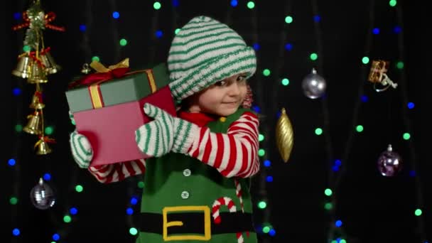 Παιδί παιδί στα Χριστούγεννα ξωτικό Άγιος Βασίλης κοστούμι βοηθός κρατώντας δώρο έκπληξη κουτί με κορδέλα — Αρχείο Βίντεο