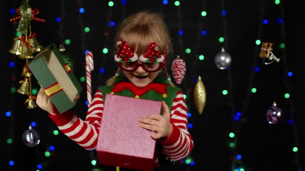 Kid κορίτσι στο Χριστουγεννιάτικο κοστούμι ξωτικό Σάντα βοηθός με δώρο κουτί, κοιτάζοντας μέσα. Καλές γιορτές. — Αρχείο Βίντεο