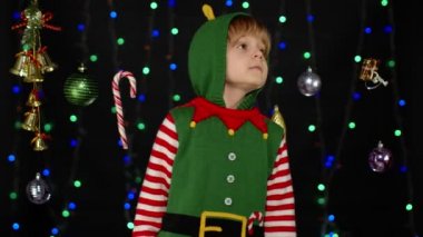 Noel Baba yardımcısı Noel Baba kostümlü çocuk sessiz kalmak için parmaklarını dudaklarına yaklaştırıyor.