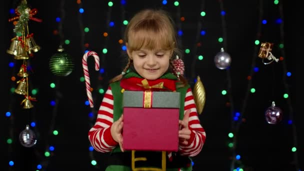 Niña en traje de ayudante de Navidad elfo Santa con caja de regalo presente, mirando dentro. Felices fiestas — Vídeos de Stock