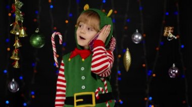 Noel Elf Noel Baba yardımcı kostümlü çocuk cep telefonuyla tebrik ediyor.