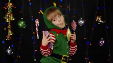 Noel Elf Noel Baba yardımcı kostümlü çocuk akıllı telefondan selfie çekiyor. Yeni yıl tatili