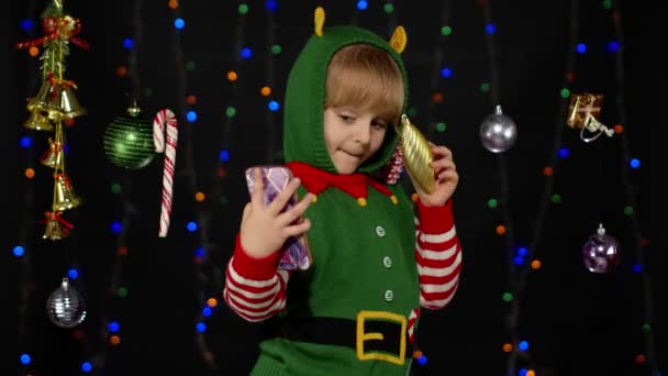 Noel Elf Noel Baba yardımcı kostümlü çocuk akıllı telefondan selfie çekiyor. Yeni yıl tatili — Stok video