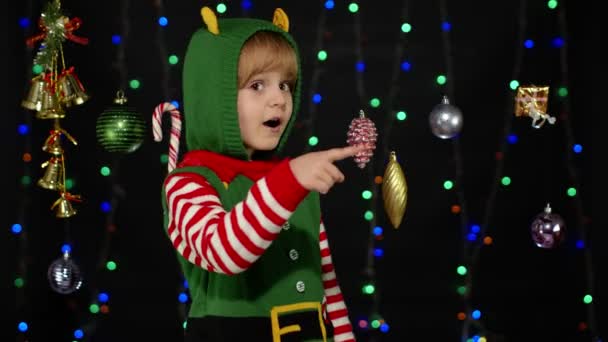 Nastoletnie dziecko dziewczyna w Boże Narodzenie elf Święty Mikołaj pomocnik kostium wskazując na coś, pokazując kciuki w górę — Wideo stockowe