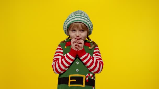 Kid girl Christmas elf Santa helper steepls fingers waiting for gift box. Child in New Year holidays — Stock Video