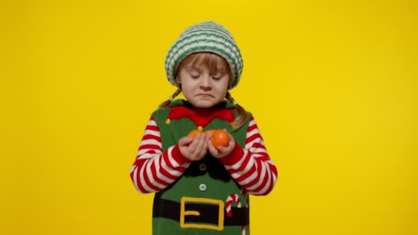 크리스마스 요정 산타 조력자 의상을 입은 소녀가 만다린 과일을 들고 있습니다. 새해 기념행사 — 비디오