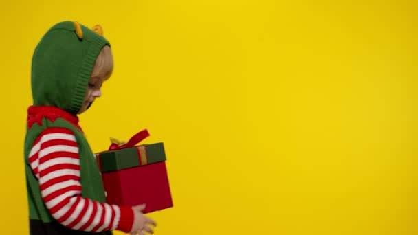 子供の女の子クリスマスエルフサンタヘルパーは、カメラにプレゼントボックスを与えます。明けましておめでとうございます。 — ストック動画