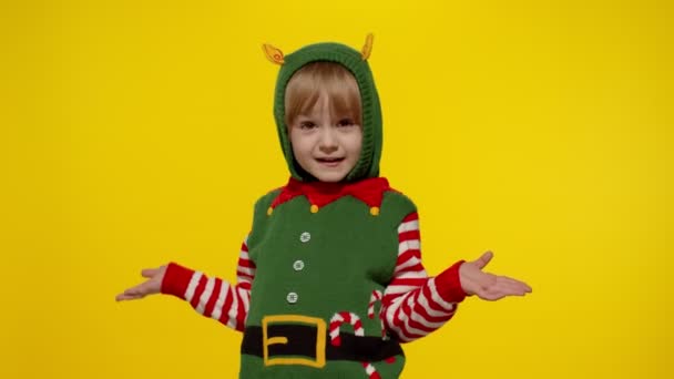 Niña impactada en traje de ayudante de Navidad elfo de Santa. Niño mirar a la cámara y hacer una pregunta lo que — Vídeos de Stock