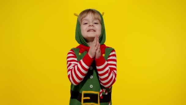 Niño en Navidad elfo Santa ayudante traje ruega, reza por los regalos en Año Nuevo. Mantiene las palmas juntas — Vídeo de stock