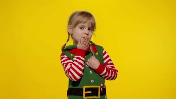 Stydí dítě dívka v vánoční elf Santa helper kostým pózování vypadající fotoaparát, fouká vzdušný polibek — Stock video