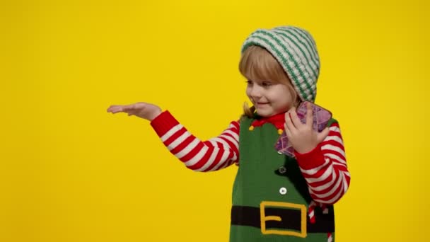 圣诞精灵中的小女孩圣诞老人的助手们把手指指向空白的空间展示广告区 — 图库视频影像