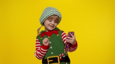 Noel Elf Noel Baba yardımcı kostümlü çocuk cep telefonuyla video görüşmesi yapıyor.