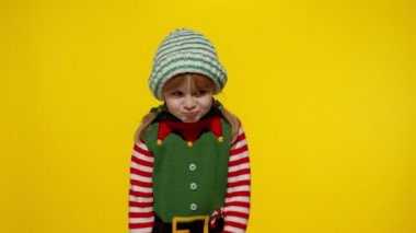 Noel Elf kılığında dağılmış bir kız çocuğu Noel Baba yardımcı kostümü başparmağını aşağıda tutuyor ve hoş olmayan hareketler gösteriyor.