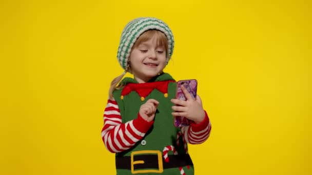 Dziecko dziewczynka w Boże Narodzenie elf Pomocnik Świętego Mikołaja kostium podejmowania rozmowy wideo na telefon komórkowy — Wideo stockowe