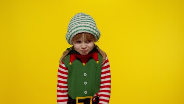 Elutasított kislány karácsonykor manó Mikulás segítő jelmez tartja hüvelykujját le, és azt mutatja, nem szeret gesztus — Stock videók