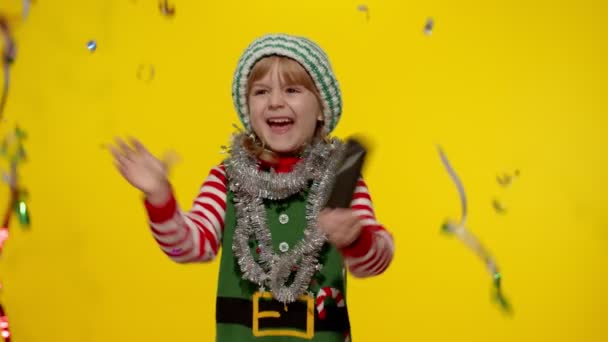 Παιδί κορίτσι έφηβος στο Χριστουγεννιάτικο ξωτικό Σάντα στολή βοηθού διασκεδάζοντας χαίρεται πάνω από κομφετί βροχή — Αρχείο Βίντεο