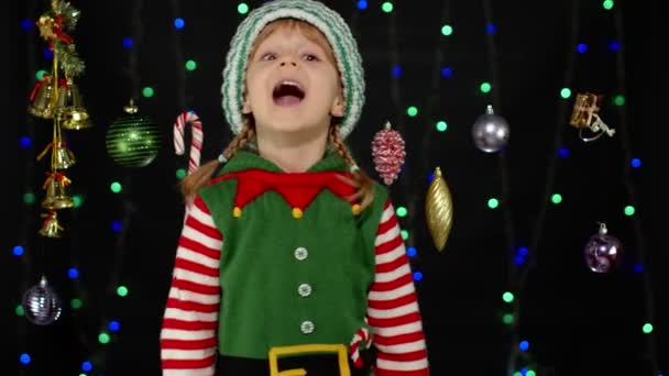 Teen kid girl in Christmas elf Santa Claus helper costume showing thumbs up on black background — Stock Video