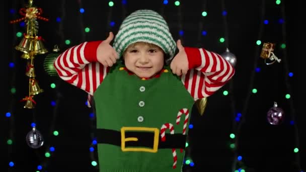 Teen kid girl in Christmas elf Weihnachtsmann Helfer Kostüm zeigt Daumen nach oben auf schwarzem Hintergrund — Stockvideo