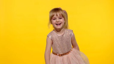 Sarışın genç kız 5-6 yaşlarında poz veriyor. Çocuk surat asıyor, oynaşıyor, dans ediyor.