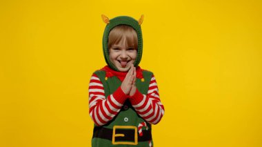 Küçük kız Noel Elfi Noel Baba hediye kutusunu beklerken dilini gösteriyor. Yılbaşı tatilindeki çocuk