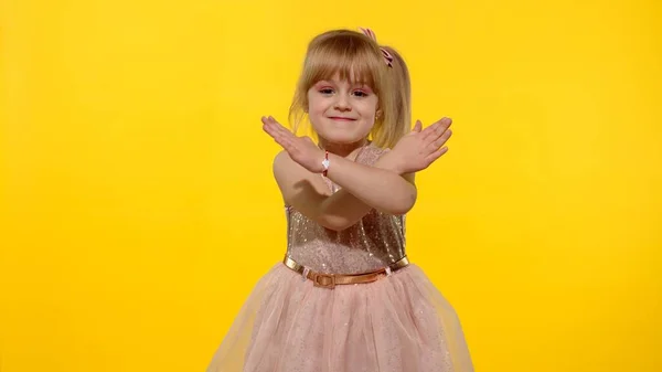 Kind meisje kijkt naar camera gekruiste handen tonen stop gebaar op gele achtergrond. Langzame beweging — Stockfoto