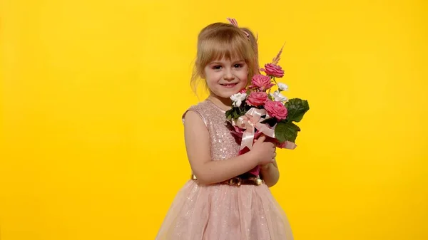 Klein kind meisje met mode make-up staan met boeket van bloemen geïsoleerd op gele achtergrond — Stockfoto