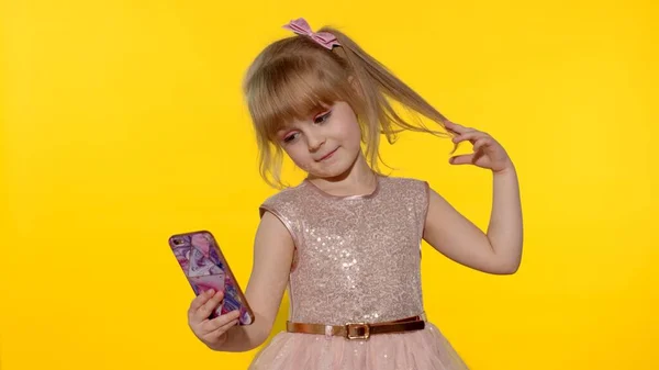 Menina criança usando smartphone. Retrato de criança loira emocionalmente faz selfie no telefone celular — Fotografia de Stock