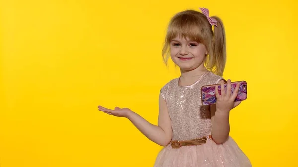 Niño señalando algo con las manos, mostrando, ofreciendo un producto. Niña sosteniendo teléfono inteligente — Foto de Stock