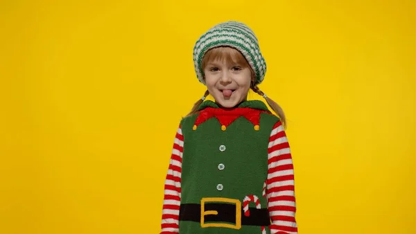 穿着圣诞精灵圣诞老人助手服装的小女孩笑着，鬼鬼祟祟的。新年庆祝活动 — 图库照片