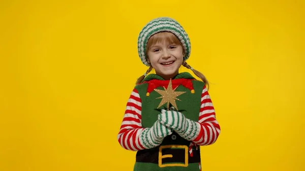 Дитяча дівчинка в різдвяному ельфійському костюмі Санта помічника тримає зіркову іграшку і робить бажання. Новорічне свято — стокове фото