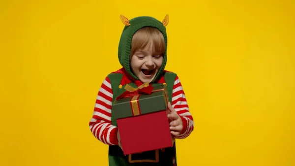 Дитяча дівчинка в різдвяному ельфійському костюмі Санта помічника отримує подарункову коробку. Новорічне свято — стокове фото