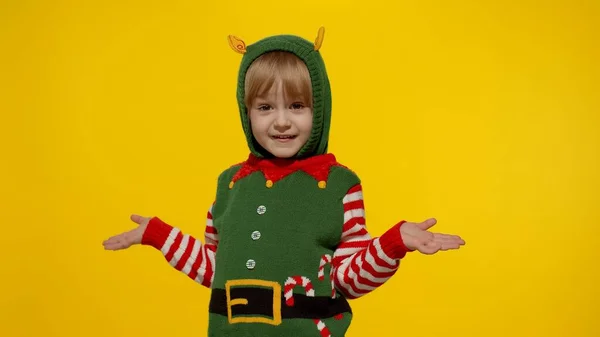 クリスマスの自己サンタヘルパーの衣装でショックを受けた子供の女の子。子供はカメラを見て質問する — ストック写真