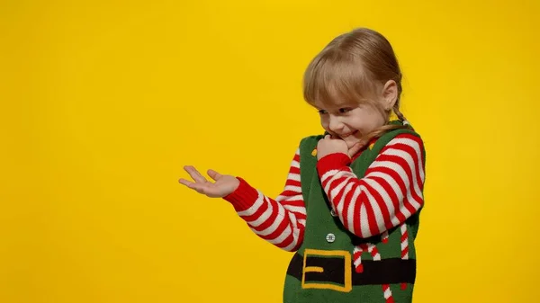 Дитяча дівчинка в різдвяному ельфі Санта помічник костюм вказує пальці в порожньому просторі показує рекламну зону — стокове фото