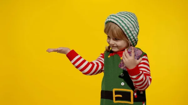Menina criança no elfo de Natal Santa ajudante traje aponta dedos no espaço em branco mostra área de publicidade — Fotografia de Stock
