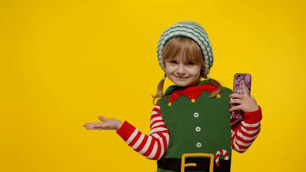 Menina criança no elfo de Natal Santa ajudante traje aponta dedos no espaço em branco mostra área de publicidade — Fotografia de Stock
