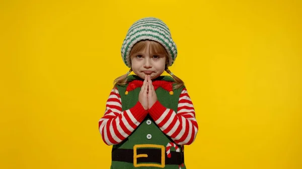 Kid in Christmas elfo Santa helper traje implora, reza sobre presentes no Ano Novo. Mantém as palmas juntas — Fotografia de Stock