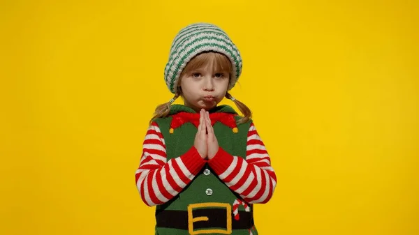 Держит ладони вместе. Мальчик в костюме помощника рождественского эльфа Санта просит, молится о подарках на Новый год — стоковое фото
