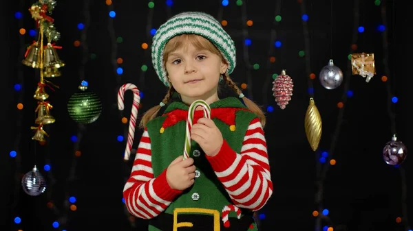 Menina no elfo de Natal Papai Noel ajudante traje lambendo doces cana pirulito caramelo doces — Fotografia de Stock