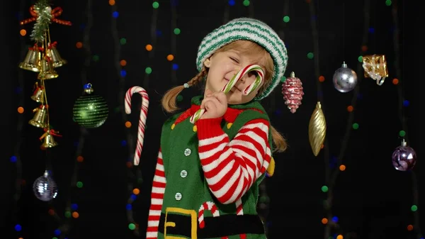 Menina criança no elfo de Natal Santa Claus traje auxiliar com doce cana pirulito alegre sorrindo — Fotografia de Stock