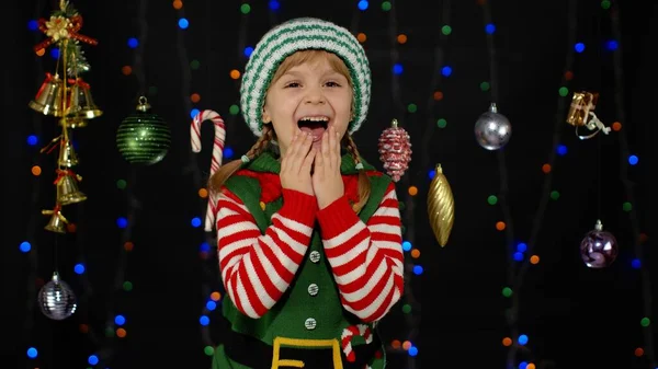 Menina criança no elfo de Natal Santa Claus ajudante traje rindo alegremente no fundo com guirlanda — Fotografia de Stock