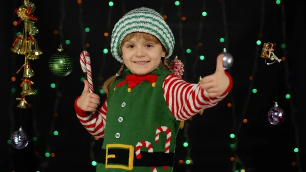 ティーン子供女の子でクリスマス自己サンタクロースヘルパー衣装ショー親指上の黒の背景 — ストック写真