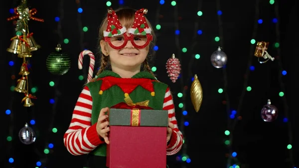 Дитяча дівчинка Різдвяний ельф Санта-помічник дарує подарункову коробку камері. Щасливі новорічні свята — стокове фото
