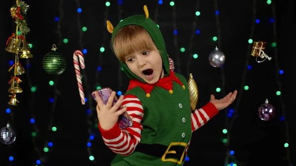 Niño niña en Navidad elfo Santa Claus ayudante traje haciendo una videollamada en el teléfono móvil — Foto de Stock