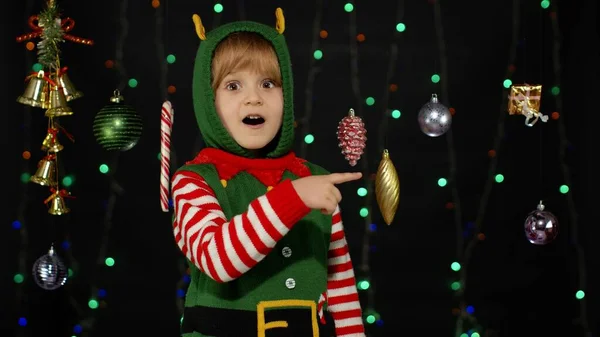 Девочка-подросток в костюме помощника рождественского эльфа Санта-Клауса указывает на что-то, показывает большие пальцы вверх — стоковое фото